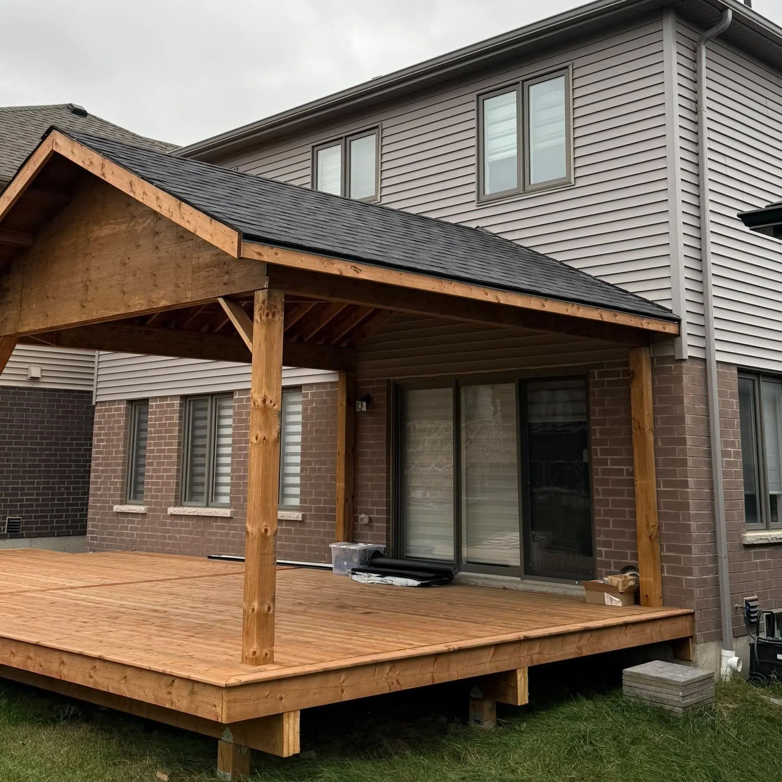 New wood deck with covered gable roof at the back of a home
