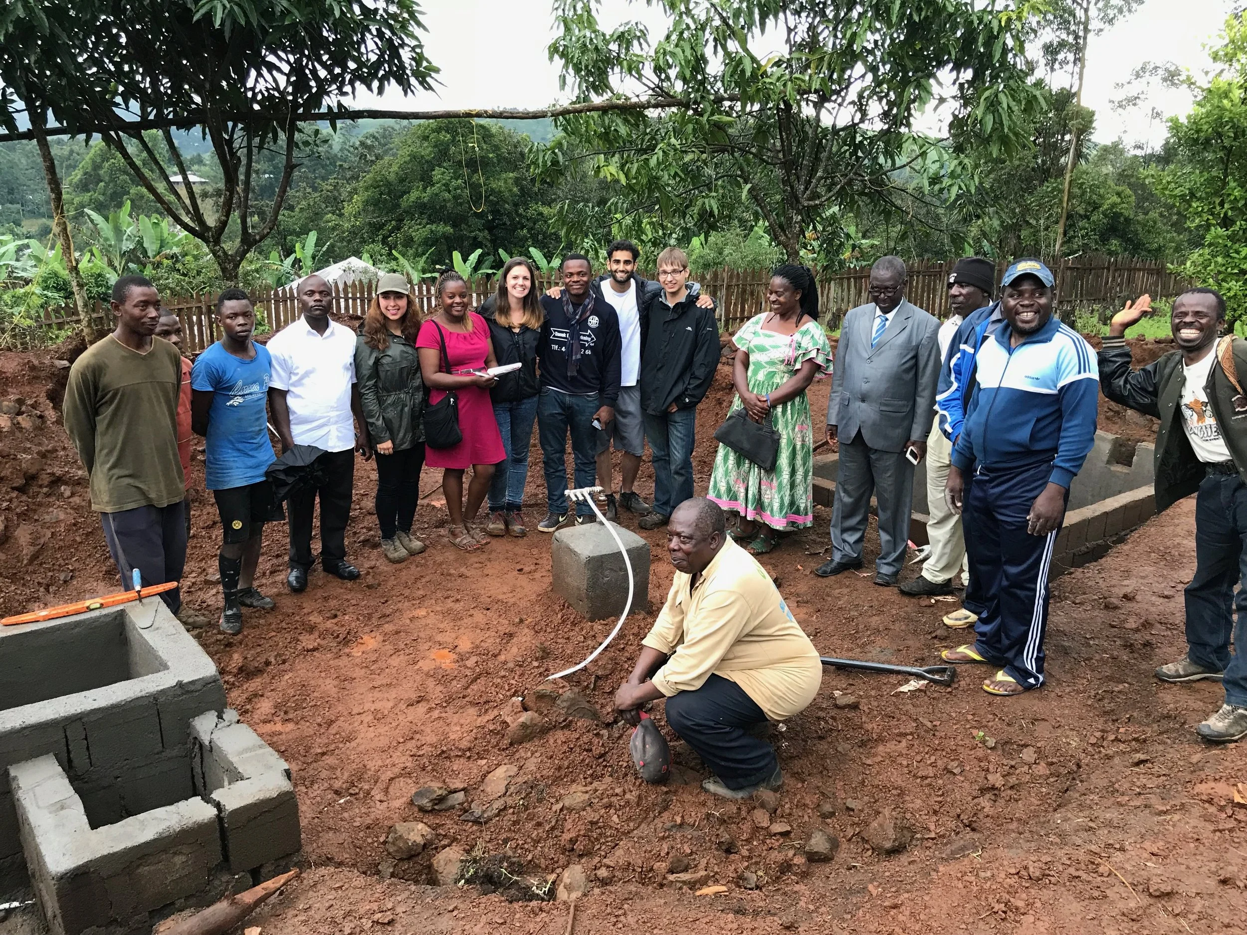 People gathered beside a construction project, with building materials and pipework in the foreground