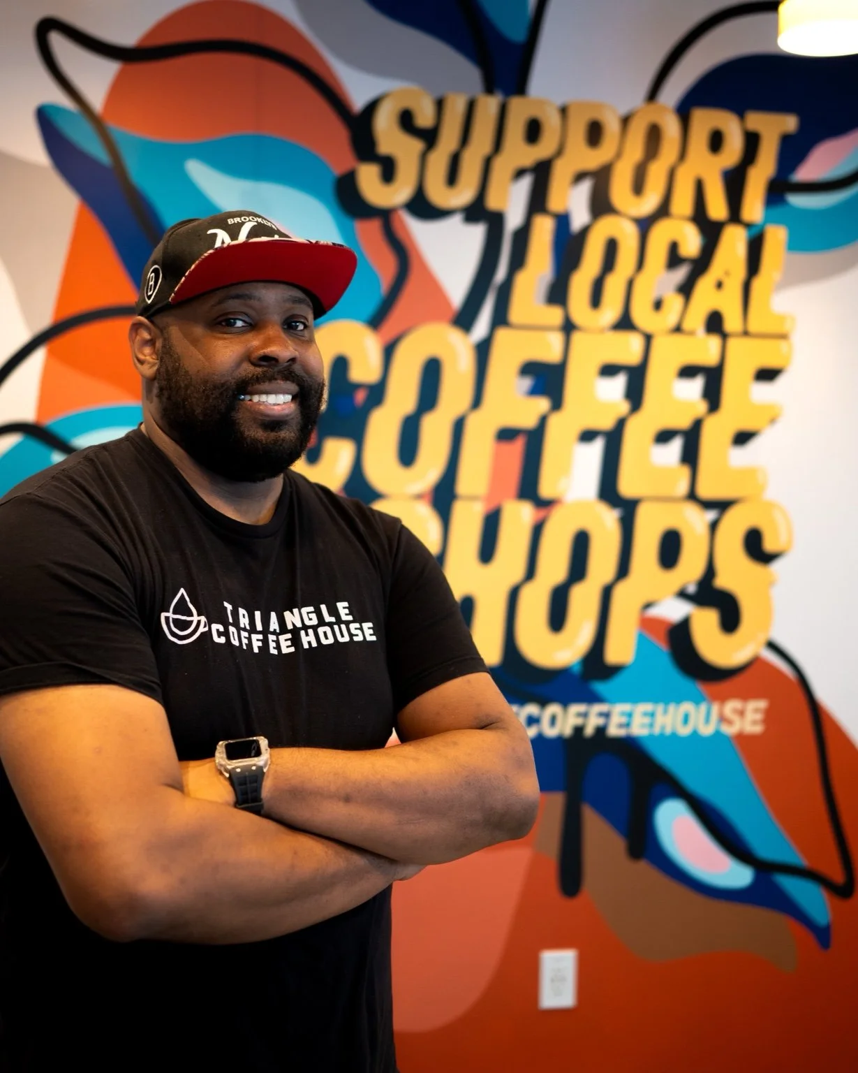 Jermaine Bantum, founder of Latte Papi, in front of the Triangle Coffee House mural
