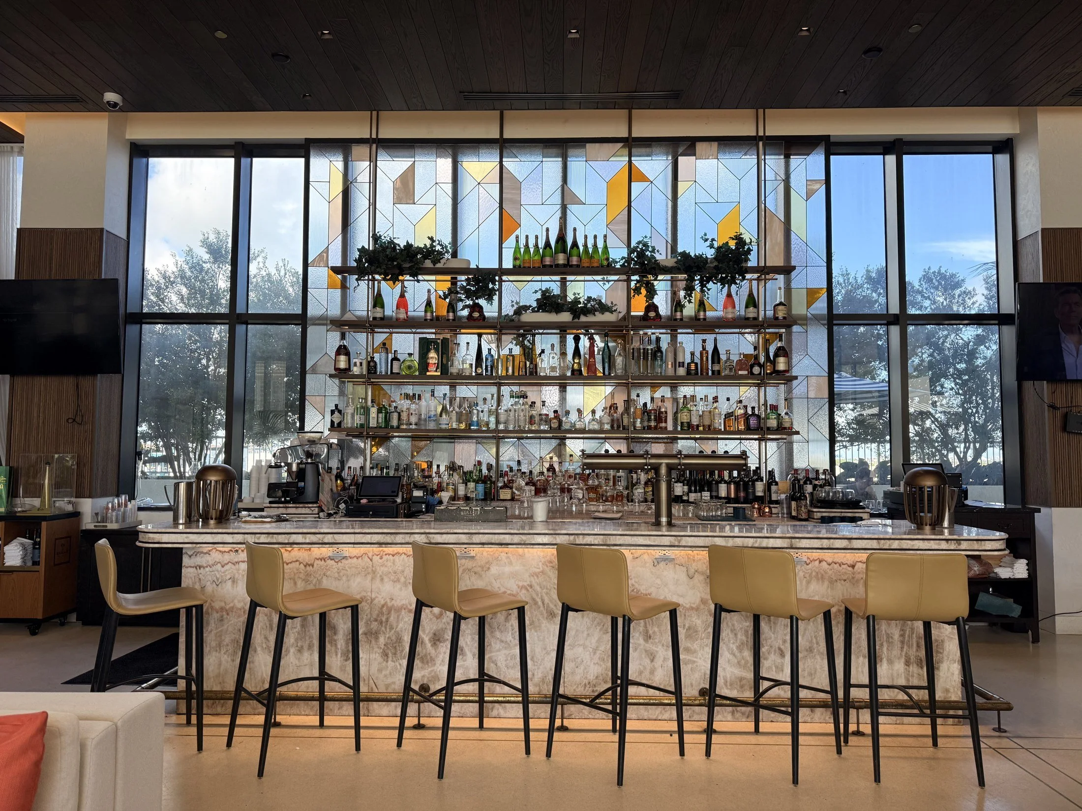 The Dalmar Fort Lauderdale lobby bar with stools, bottle display and floor-to-ceiling windows