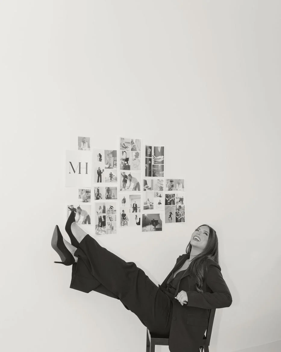 Nicole Marcus, founder of MARCETING HOUSE, in a black suit, kicking back in a studio chair
