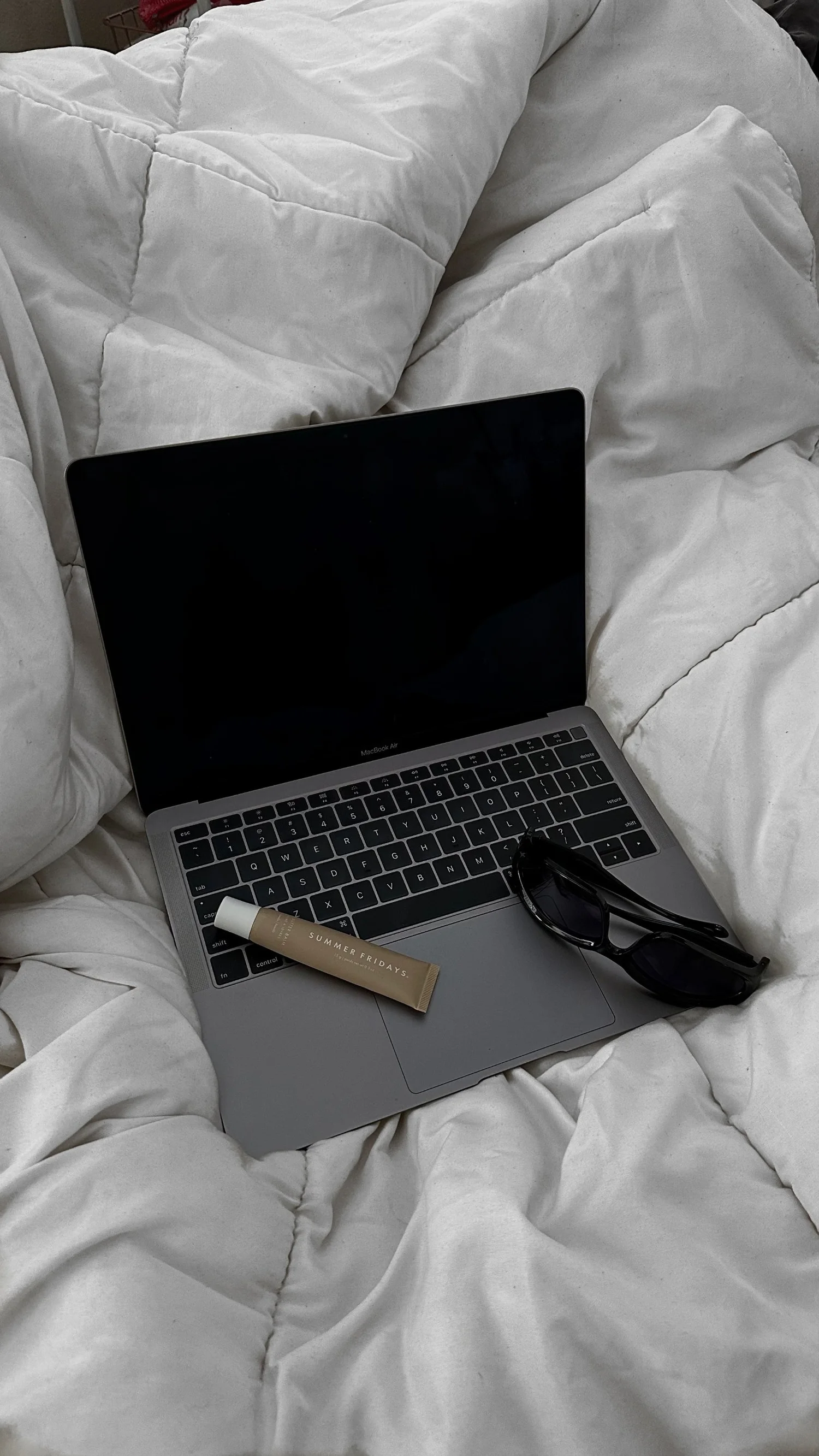 A laptop open on white bedding