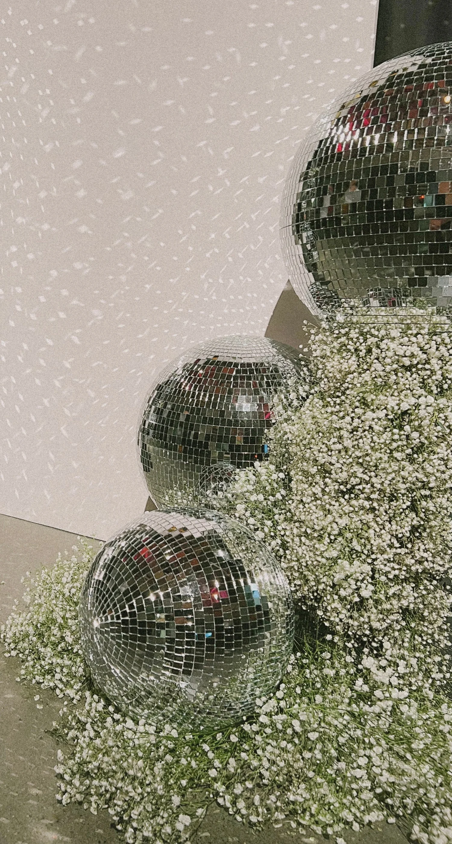 Mirrored disco balls nestled in white flowers at an event