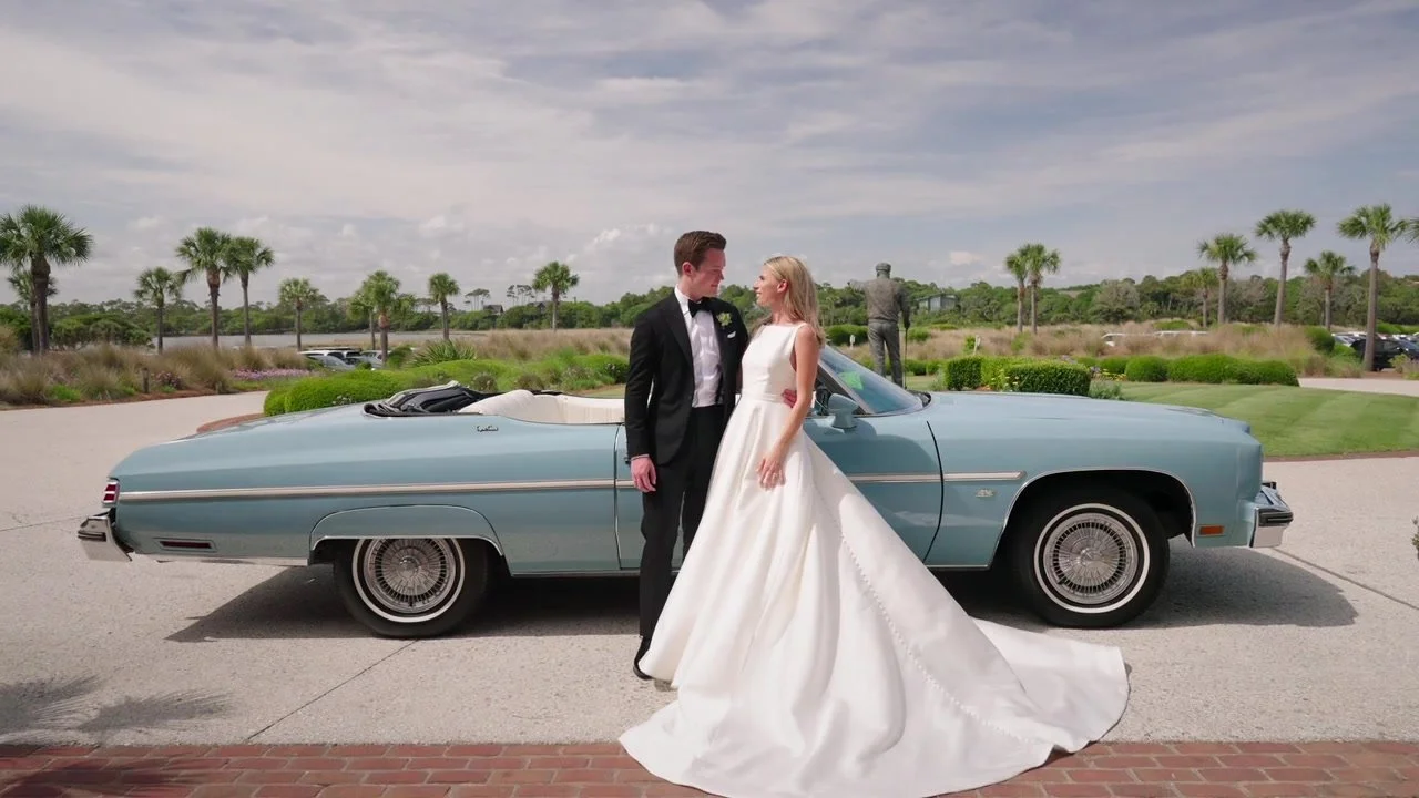 Courtney and Matt beside a classic convertible at the Ocean Course