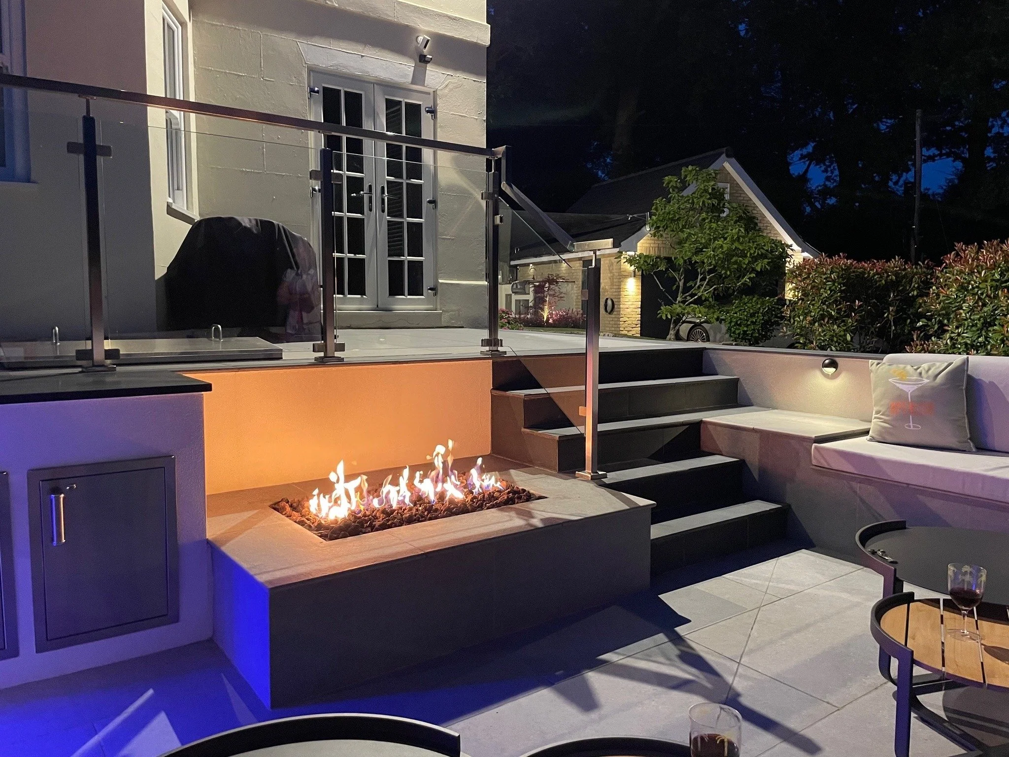The built sunken lounge at Railway House, with firelight, seating and steps back towards the house.