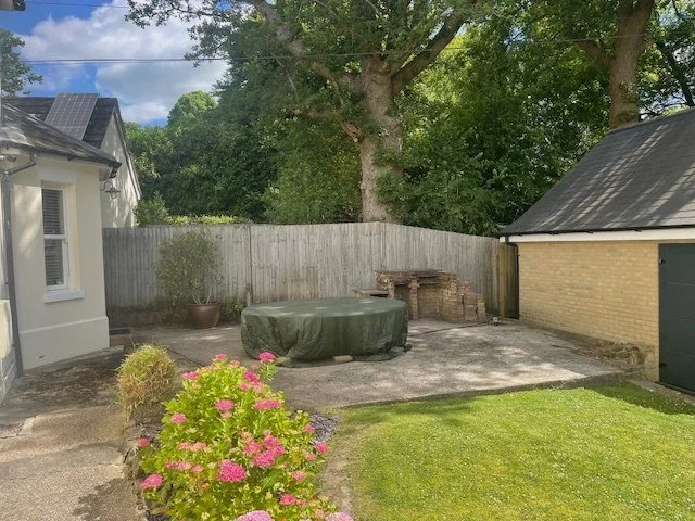 The original paved dining area between the cottage and garage, before the redesign.