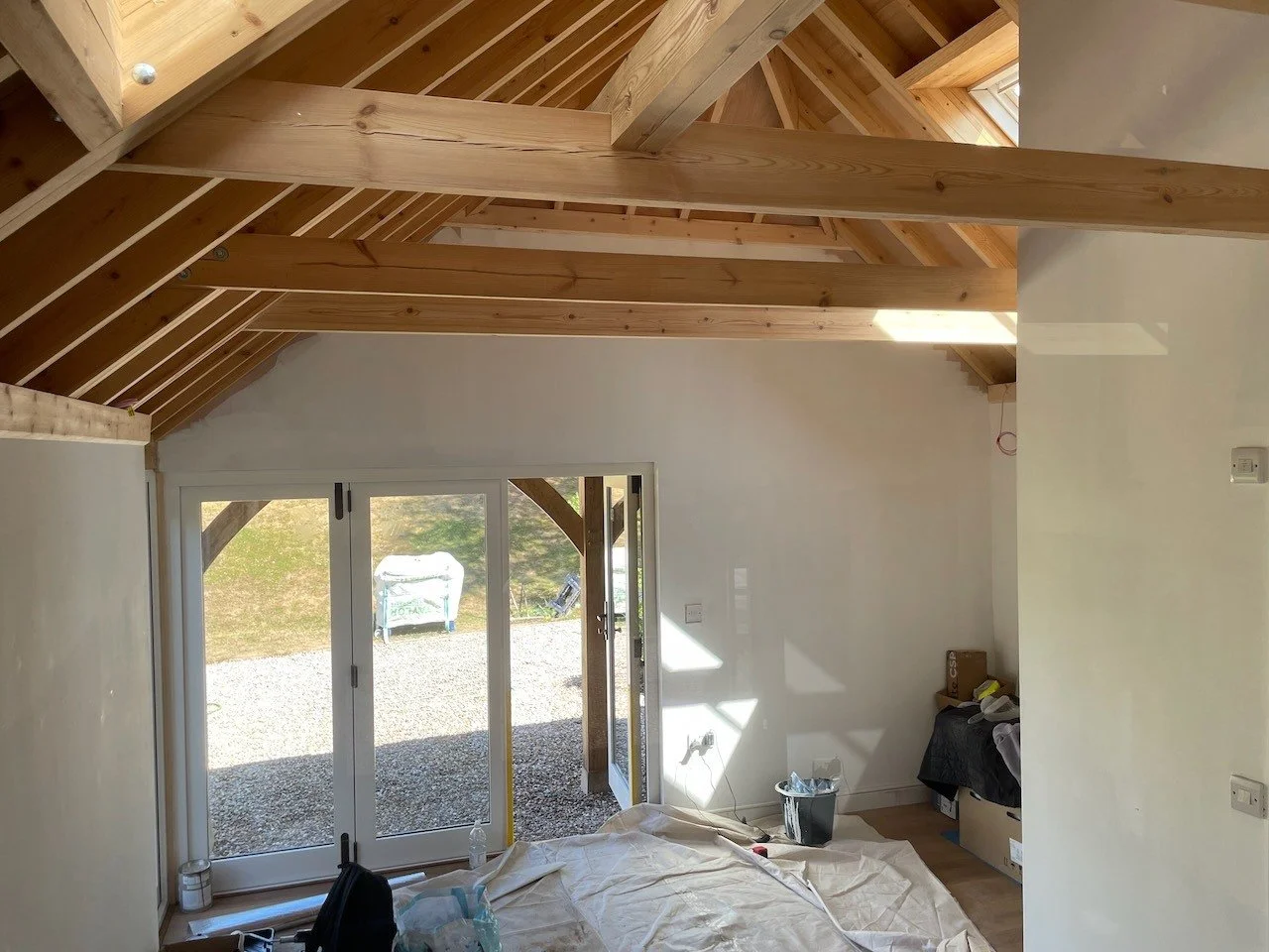 The exposed timber roof and garden-facing glazed doors during interior finishing work.