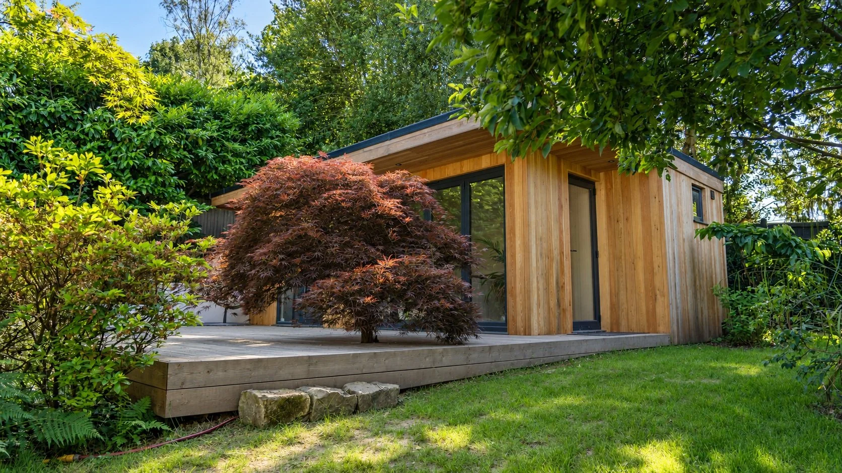 A timber garden room nestles into established trees and layered planting.
