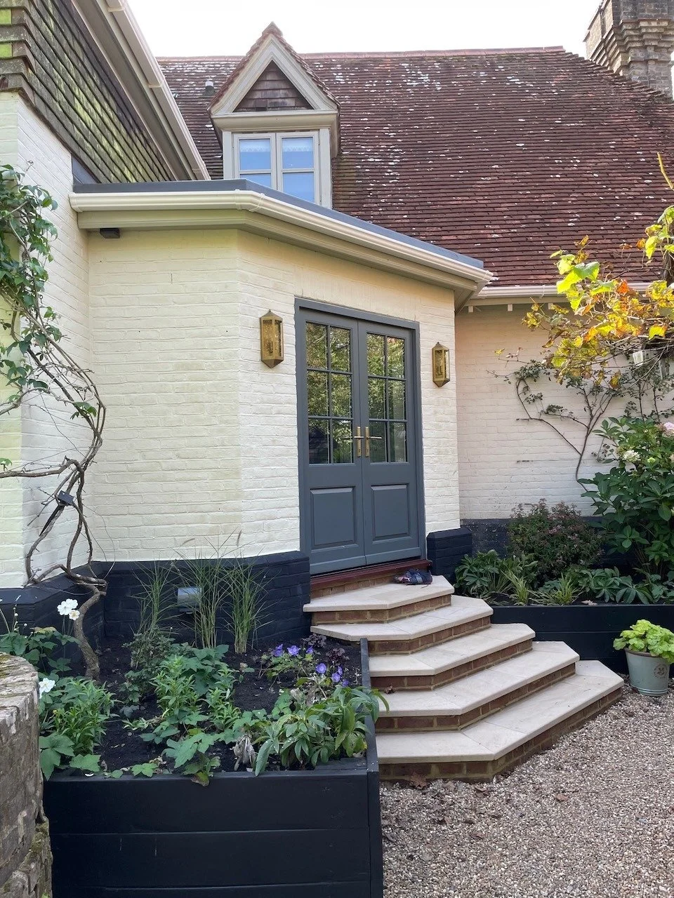 After: the new painted-brick porch with glazed double doors, stone-topped steps and surrounding planting.