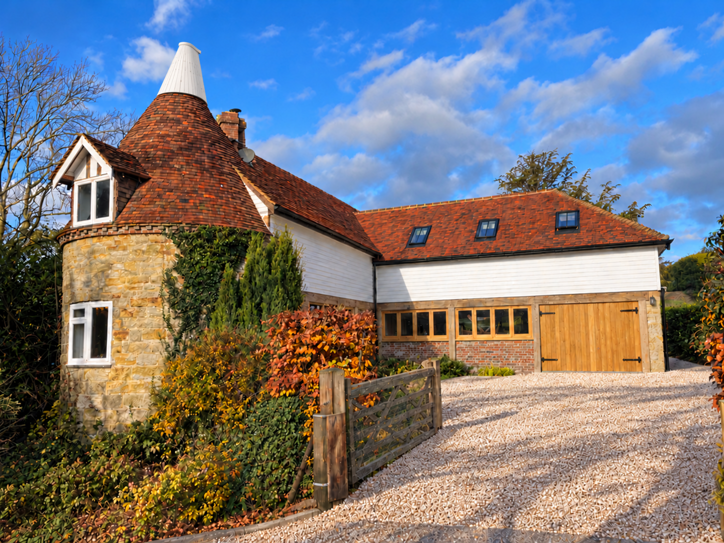 Photo-based design visualisation of the oast and adjoining house, showing the oast cowl, oak doors and a gravel approach.