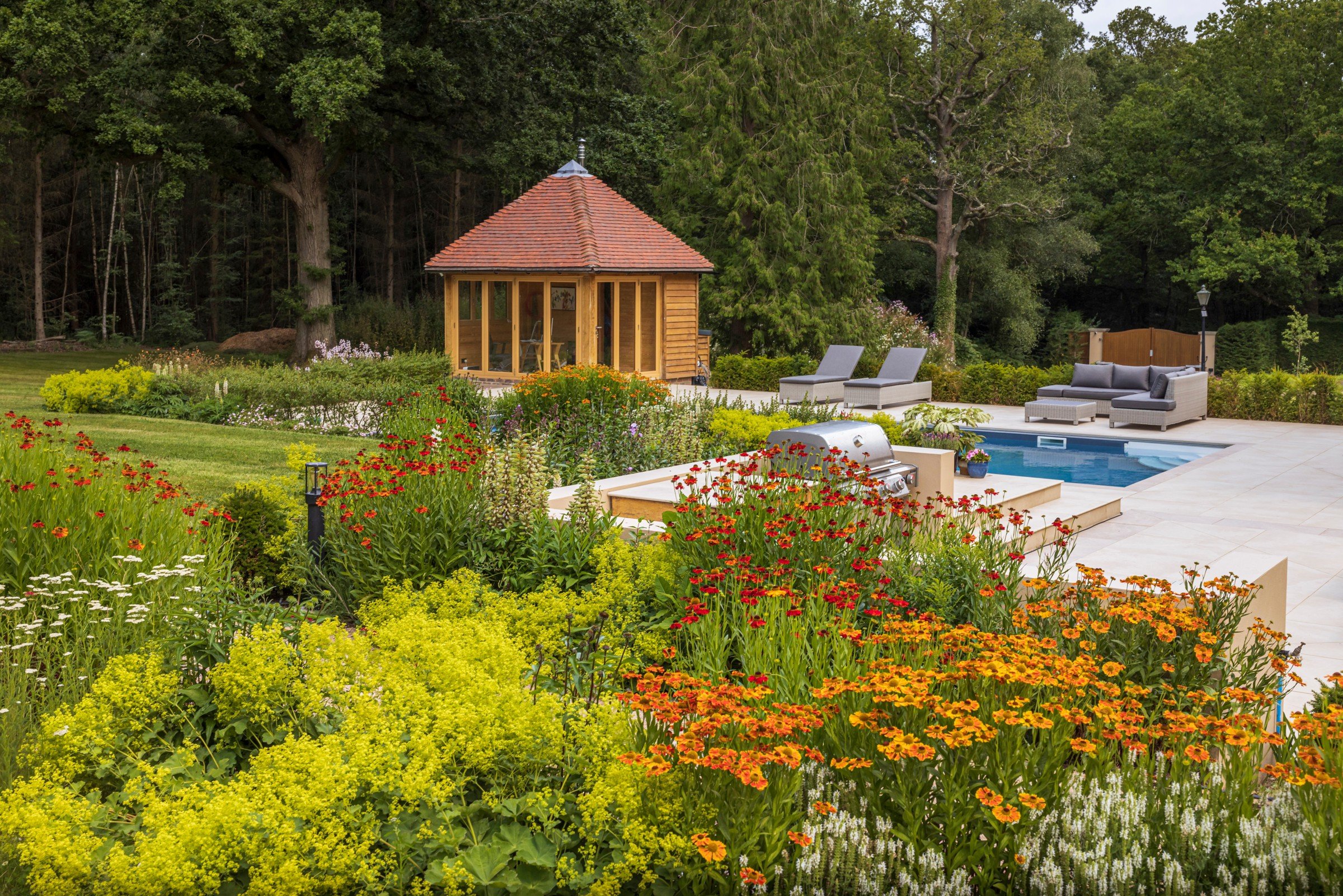 Colourful borders bring together a garden pavilion, swimming pool and outdoor seating at Fairlawns.