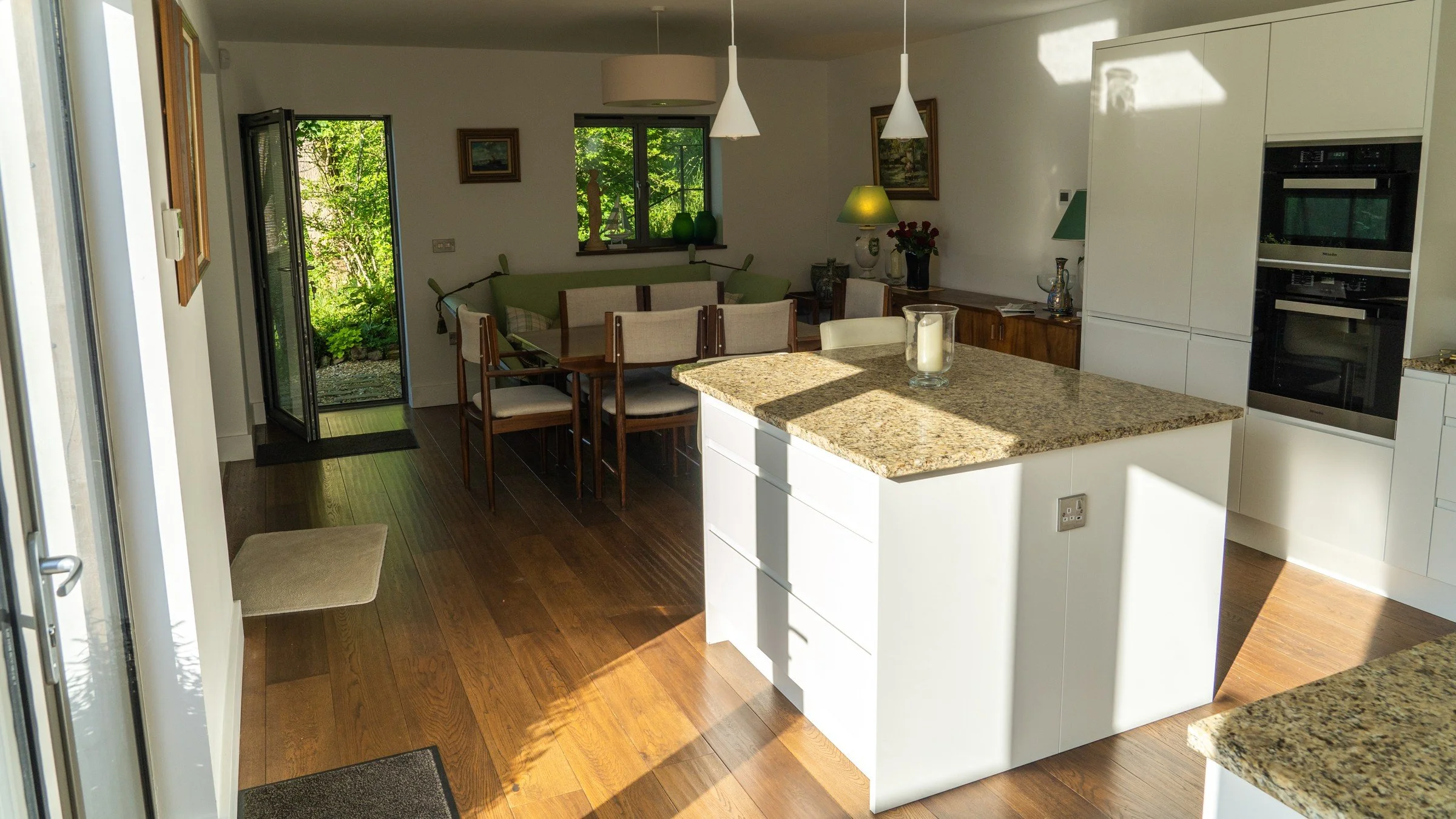 A bright kitchen and dining space with a central island and a glazed door opening onto the garden.