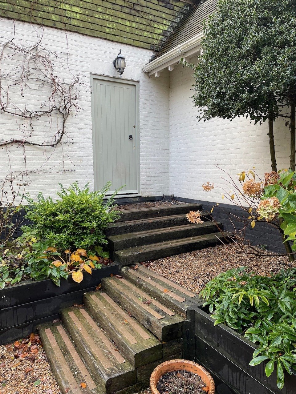 Before: a single garden door reached by several timber steps between raised planting beds.