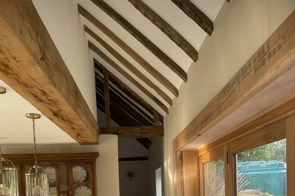 Exposed historic timber beside new glazing and plasterwork in the reworked interior.