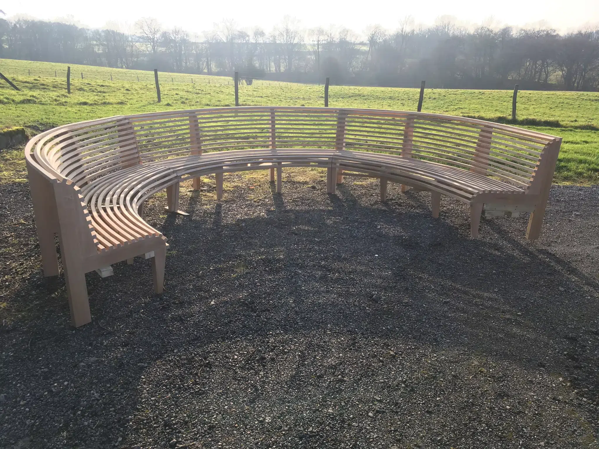 Curved oak bench sections assembled on gravel before installation in their garden setting.