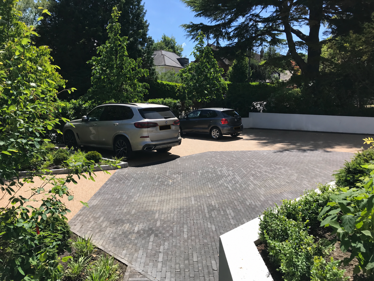 The completed driveway looking towards the road, with parking framed by trees and planting.