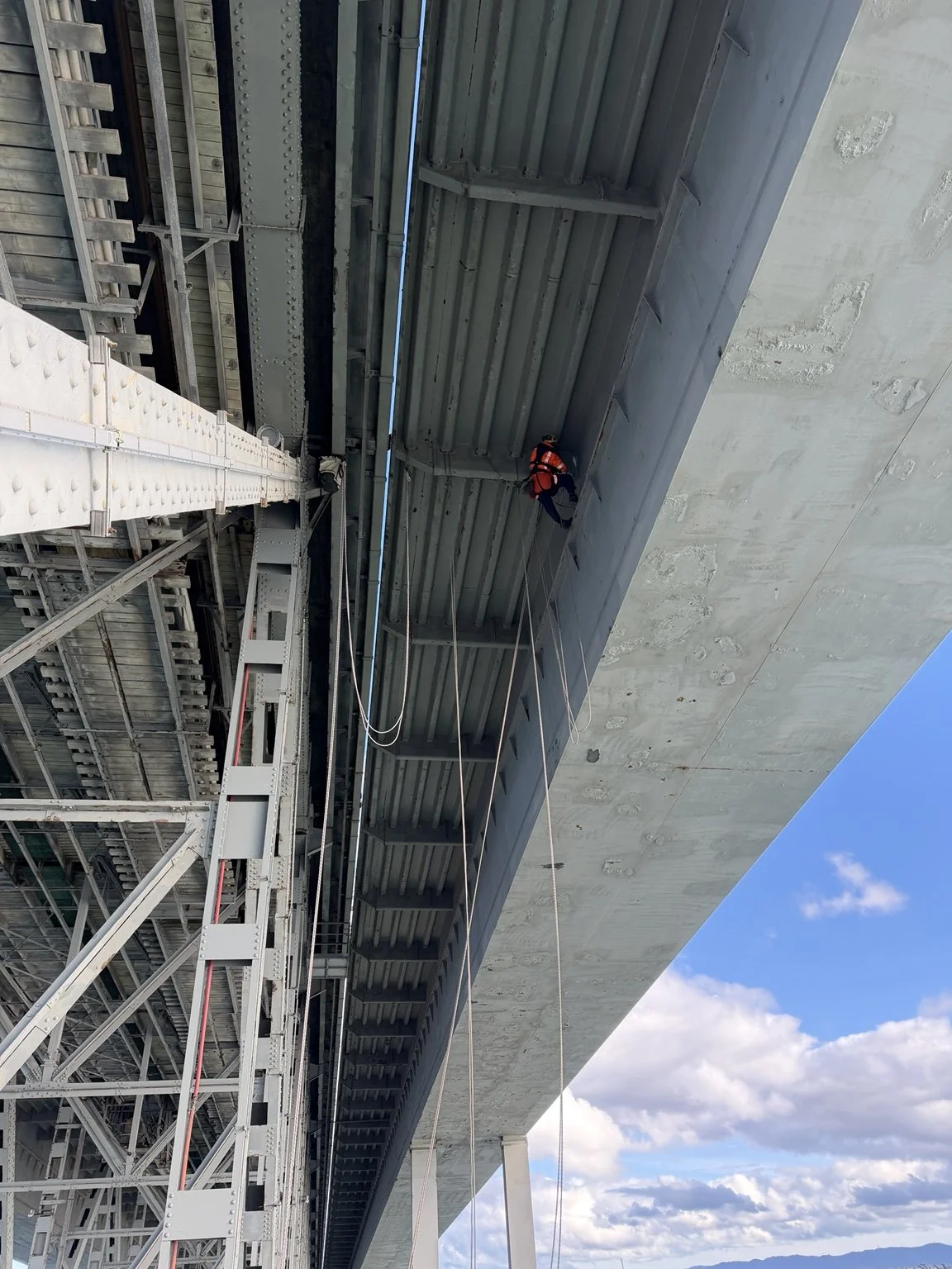 Rope access technician working beneath major bridge infrastructure