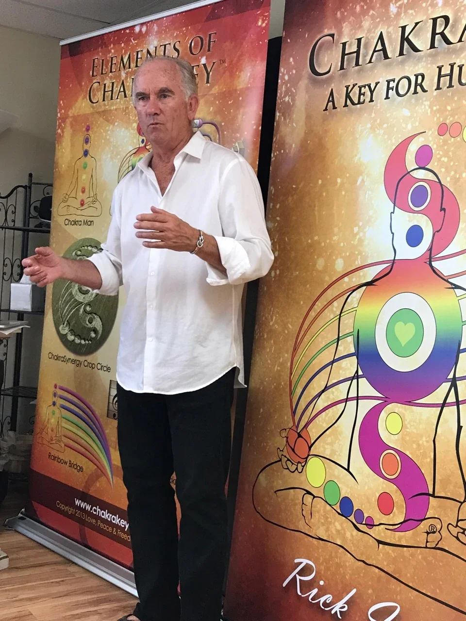 Rick Ireton wearing a white shirt, teaching beside his ChakraKey symbol displays