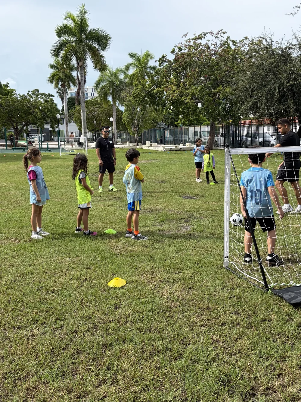 Children stand near small soccer goals during a practice activity.