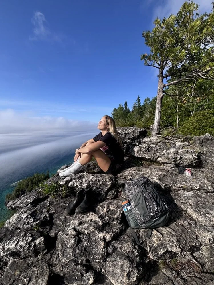 Jenni on a cliff above a sea of clouds