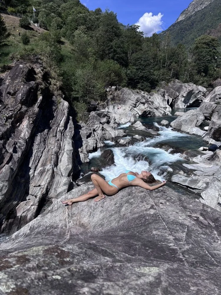 Jenni lying on river rocks