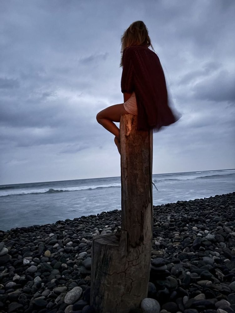 Jenni sitting on a post above the sea