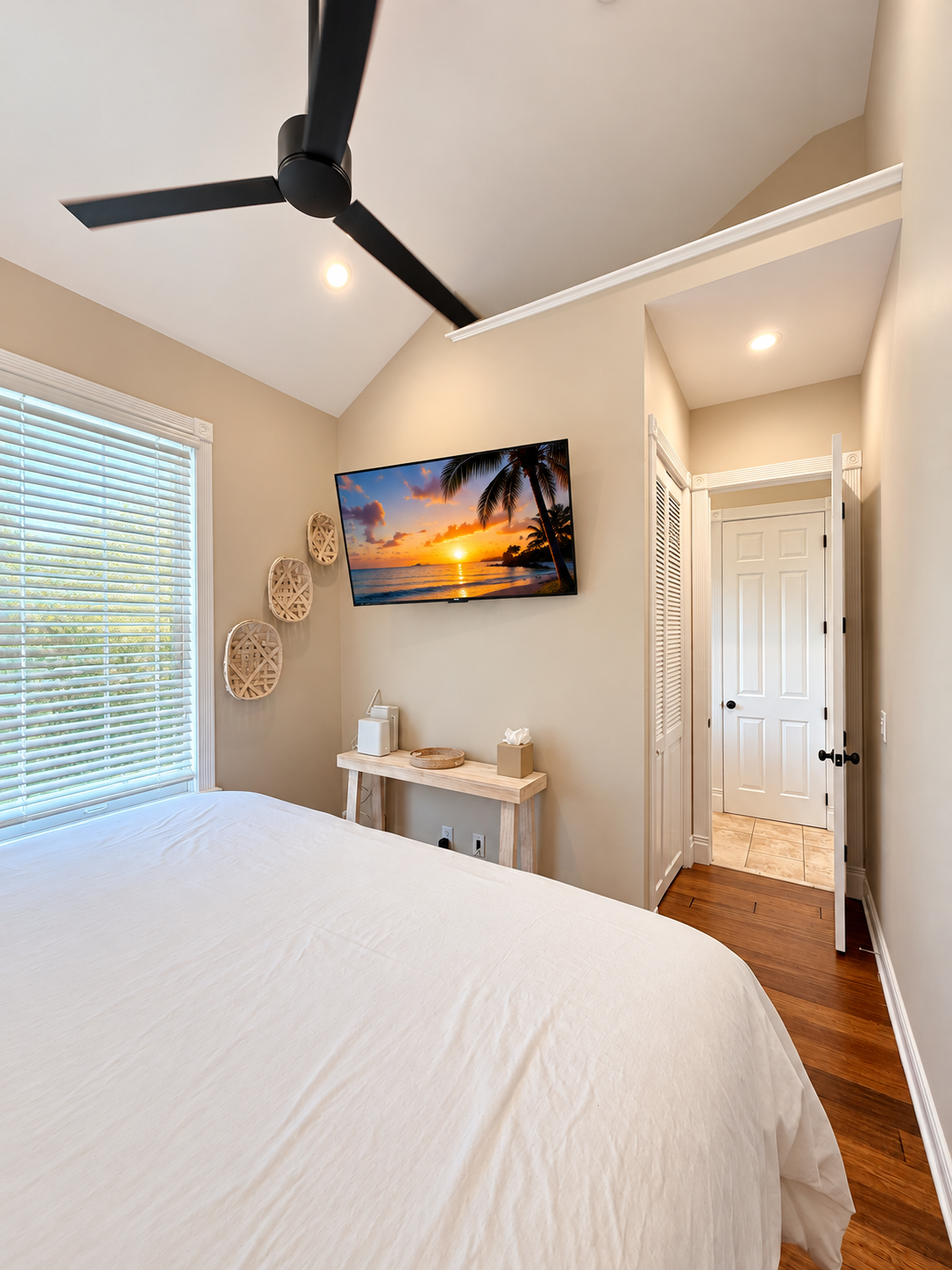 Sombrero Reef bedroom with white bedding, wall-mounted TV and doorway