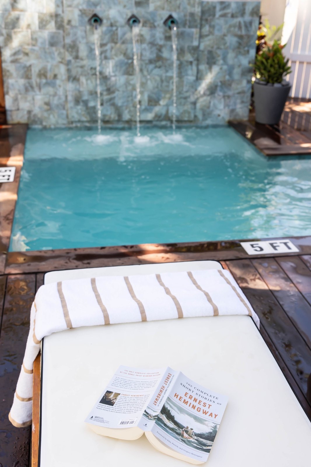 Clear pool water and waterfall feature beside an empty cushioned lounger