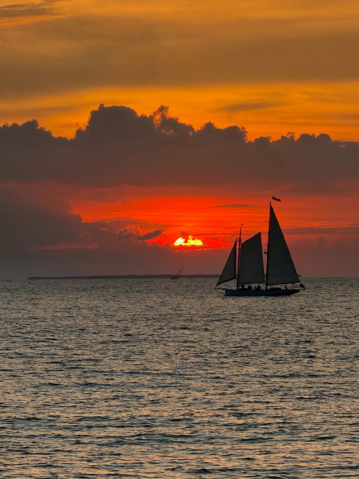 Sailboat silhouetted against a vivid Key West sunset