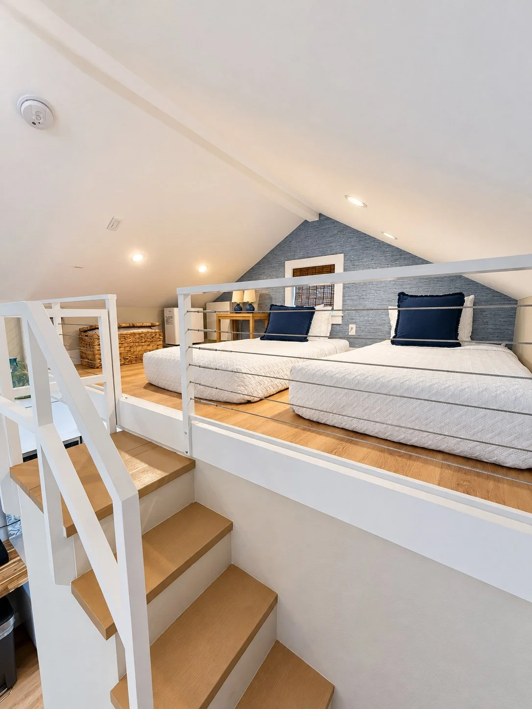 A loft room with two beds, a staircase, and a railing