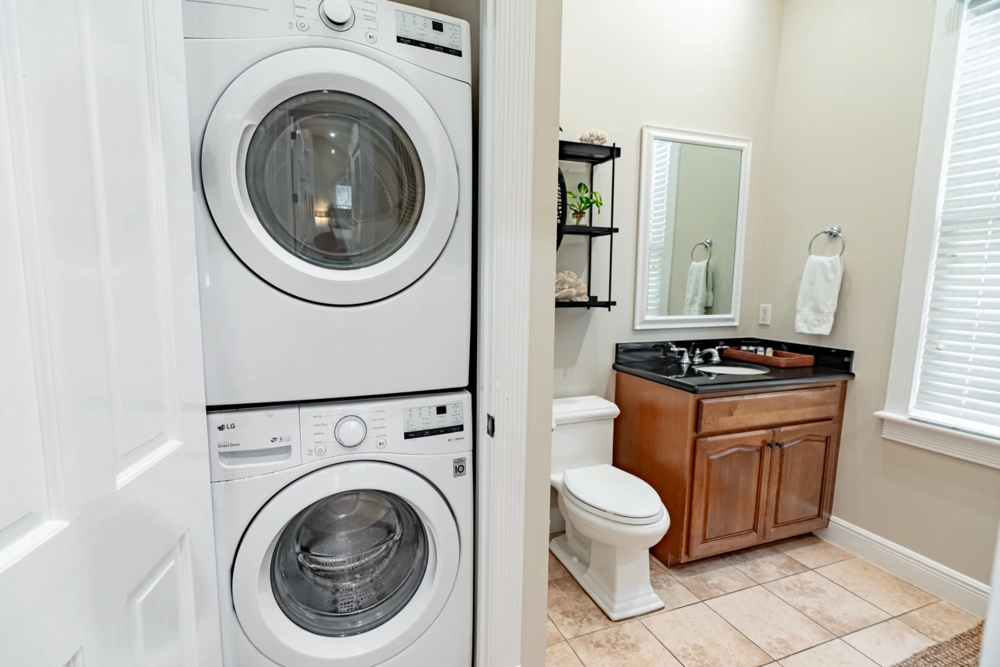 A bathroom with a stacked washer and dryer, a sink with a mirror, and a toilet.