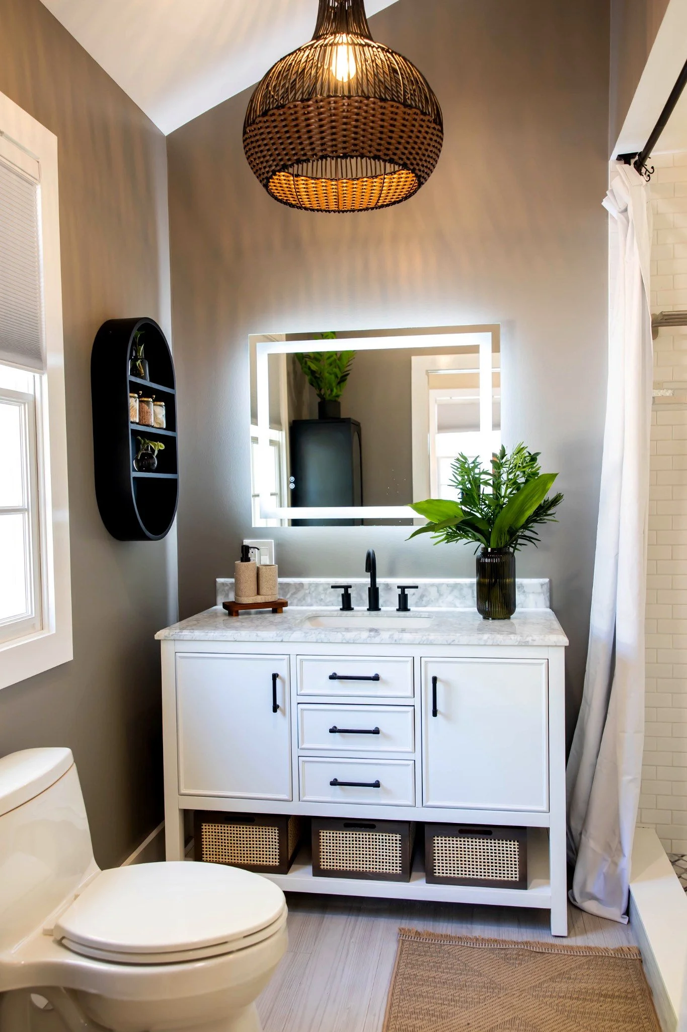 A clean and modern bathroom with a white vanity, marble countertop, and black fixtures.