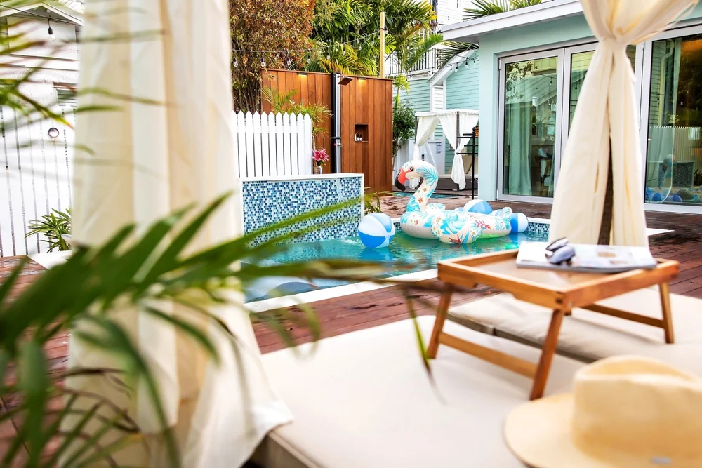 View from shaded lounge seating toward the pool, with a tropical pool float