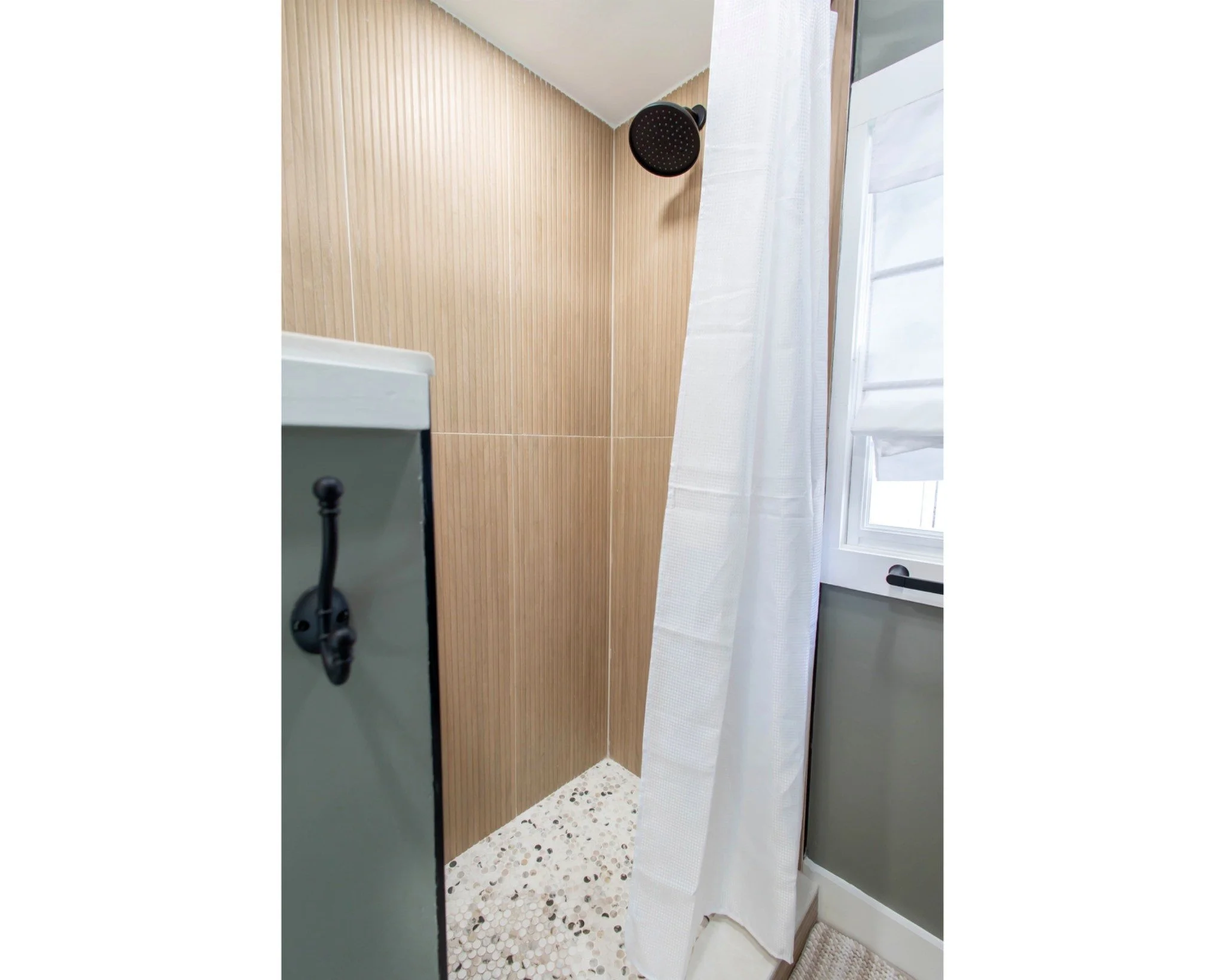 A shower with a white curtain, wood-paneled walls, and a terrazzo floor.