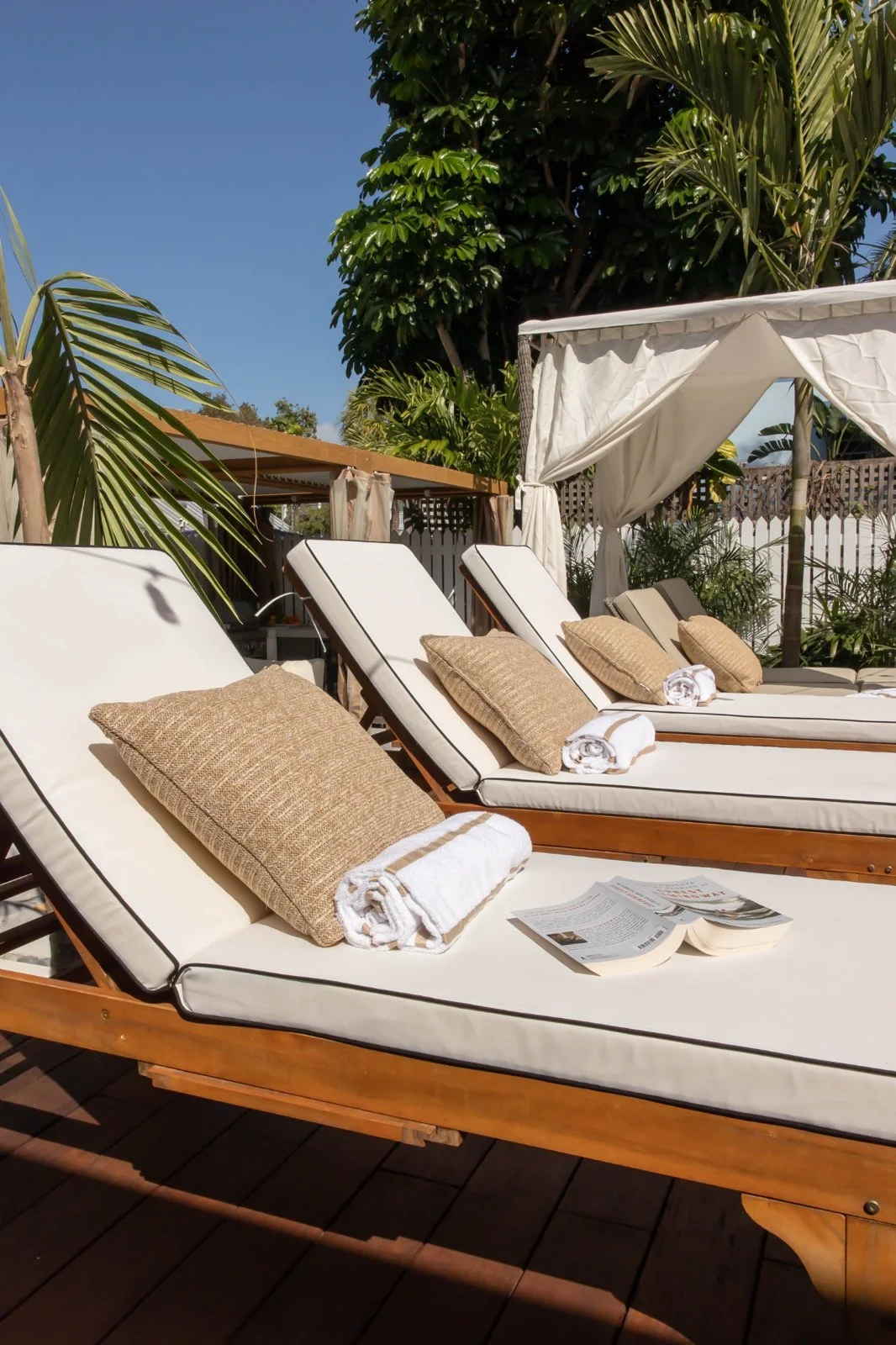 Empty cushioned sun loungers and white curtained cabana