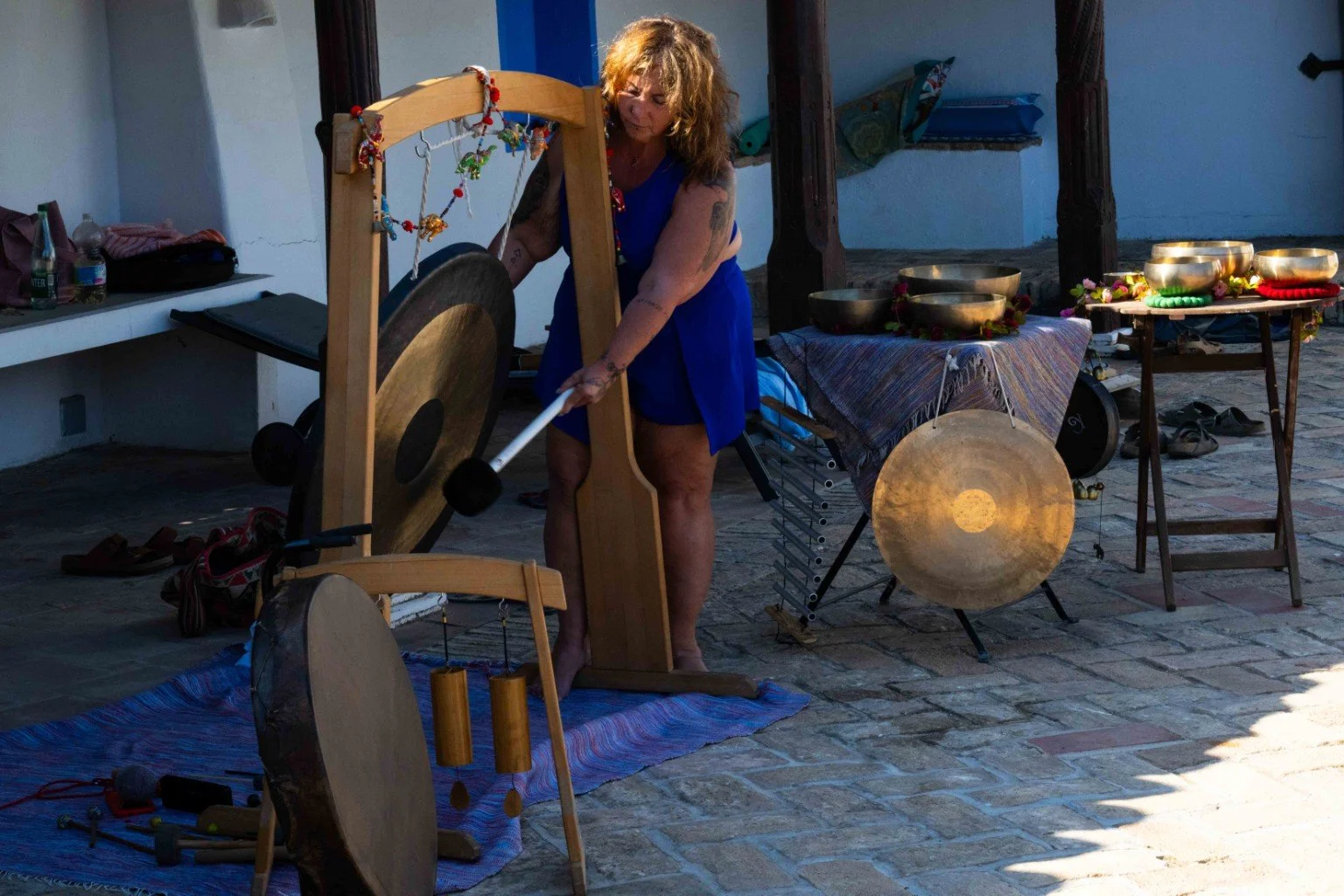 Franita playing gong surrounded by sound instruments