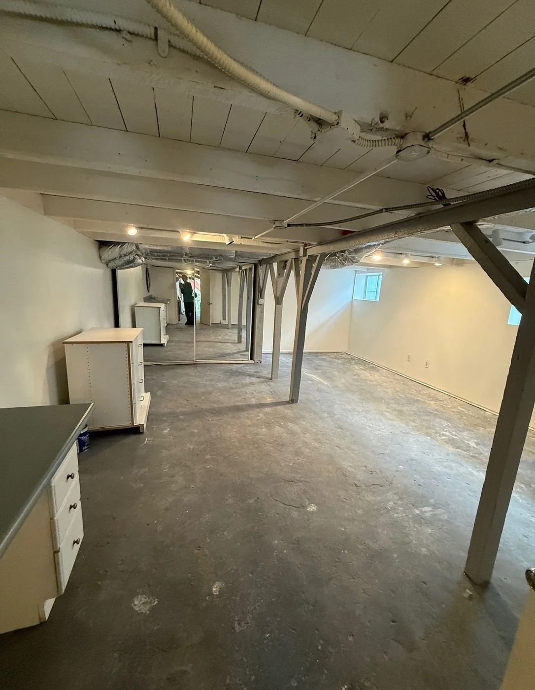Unfinished basement before: concrete floor, bare walls, a dresser