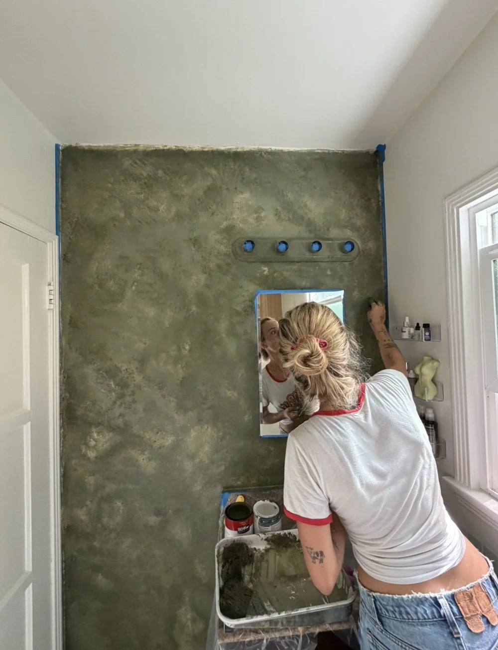 Me, applying a textured green plaster finish to a bathroom wall