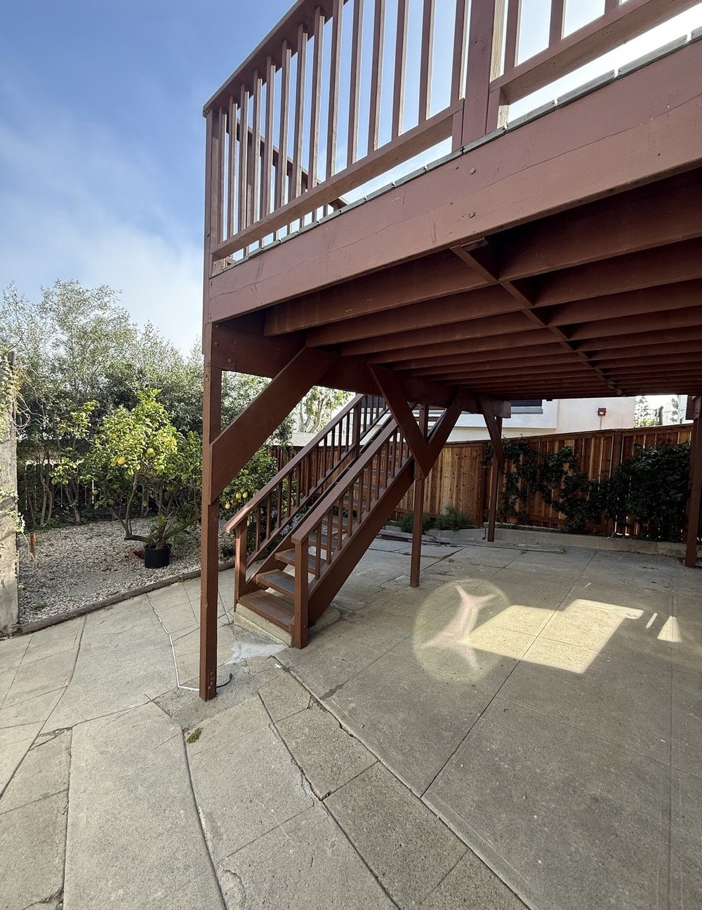 Patio before: bare concrete under the deck with an empty yard