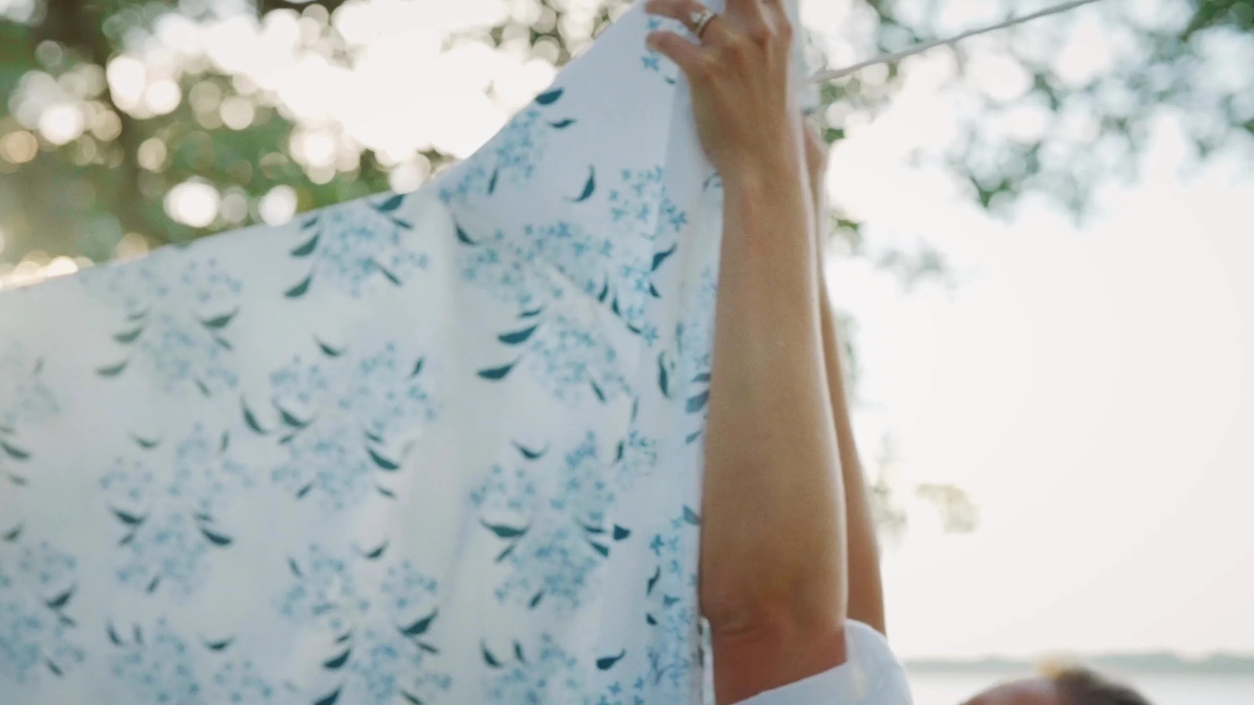 A hand holding blue patterned fabric in the light