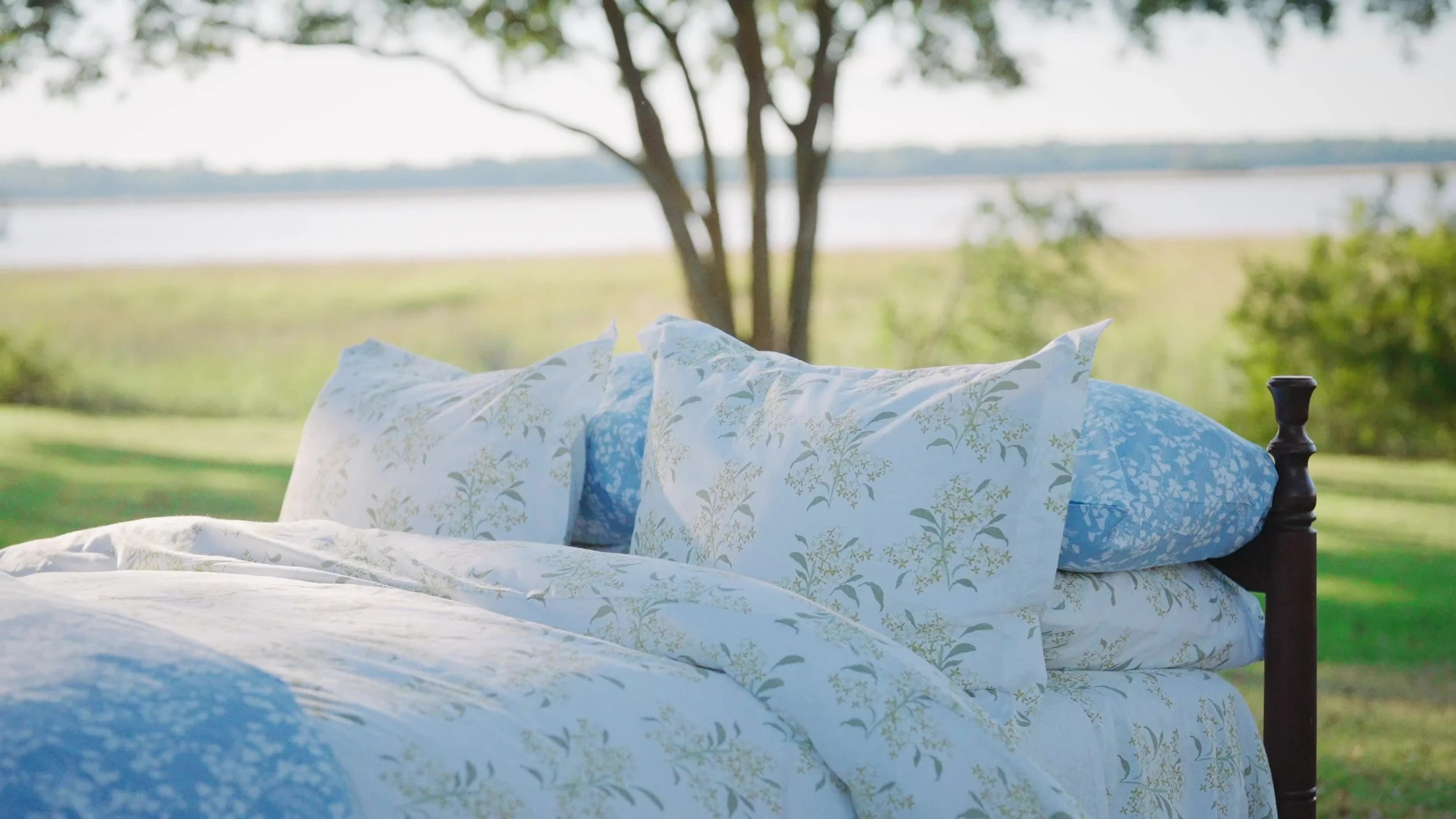 Blue and green botanical bedding beside the water, from the Jordan Connelly launch film