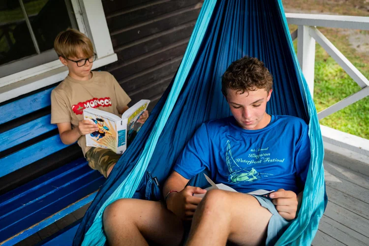 Two boys quietly reading on their cabin porch