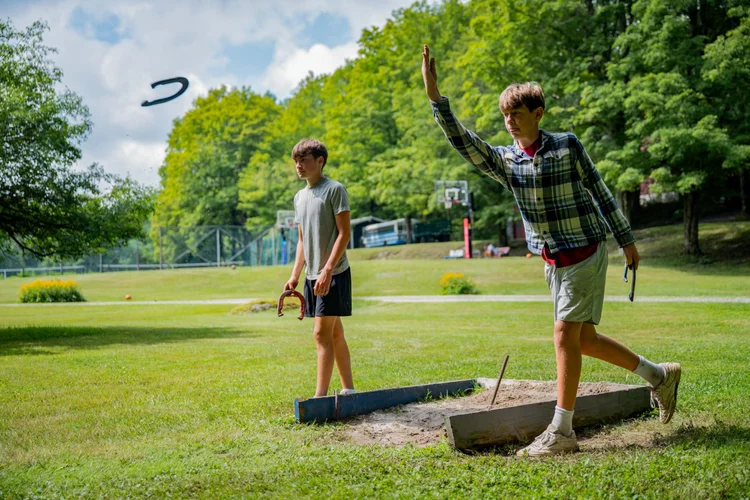 Boys playing horseshoes on sunny day