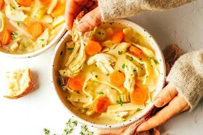Bowl of chicken soup with carrots, celery and fresh herbs