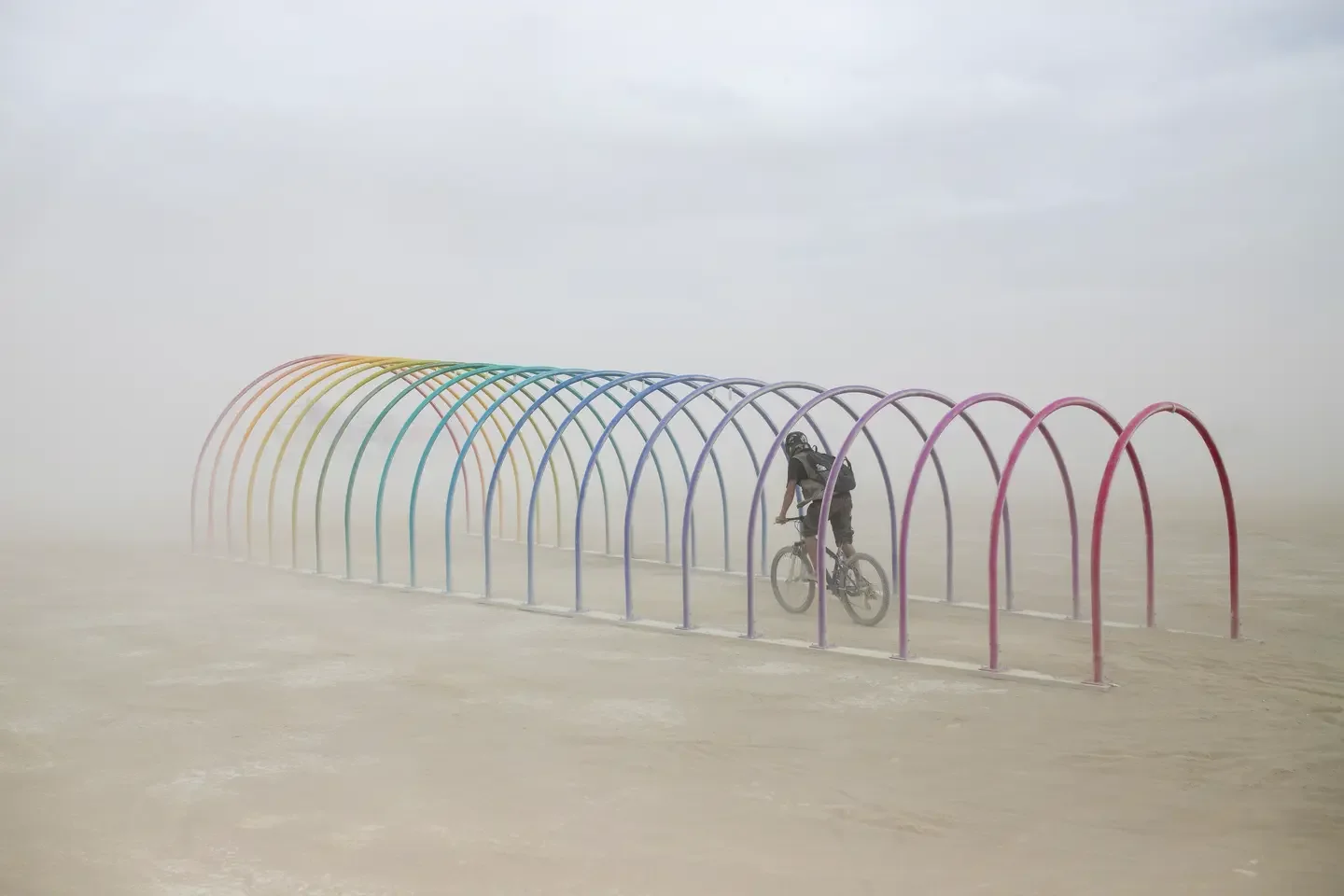 A cyclist riding through the rainbow arches in the dust