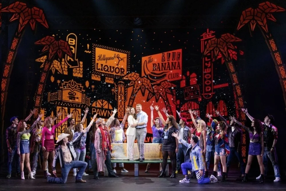 The touring company of Pretty Woman: The Musical under neon Hollywood signs in the finale