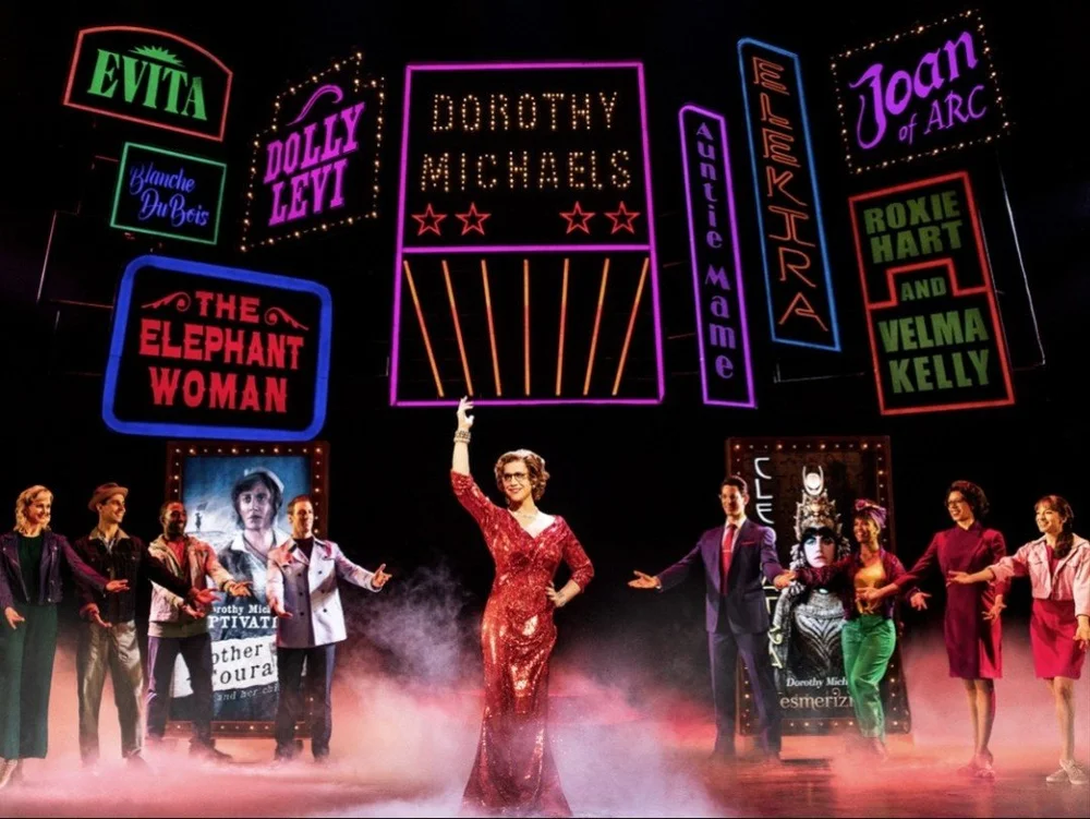Santino Fontana in a red sequined gown beneath neon marquees reading Dorothy Michaels, with the company of Tootsie
