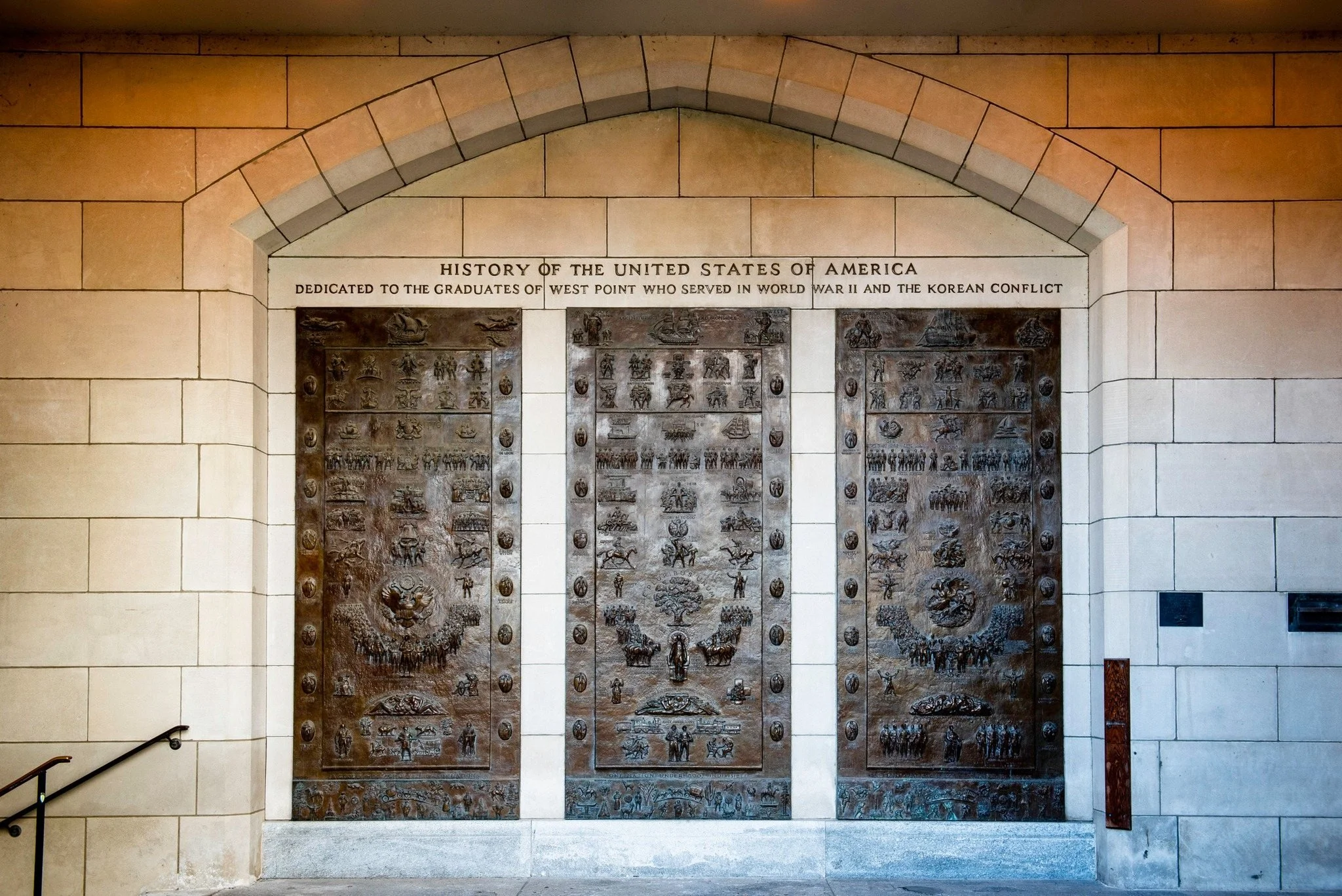The three bronze panels set into a carved stone archway at West Point, under the inscription History of the United States of America, dedicated to the graduates of West Point who served in World War II and the Korean Conflict.