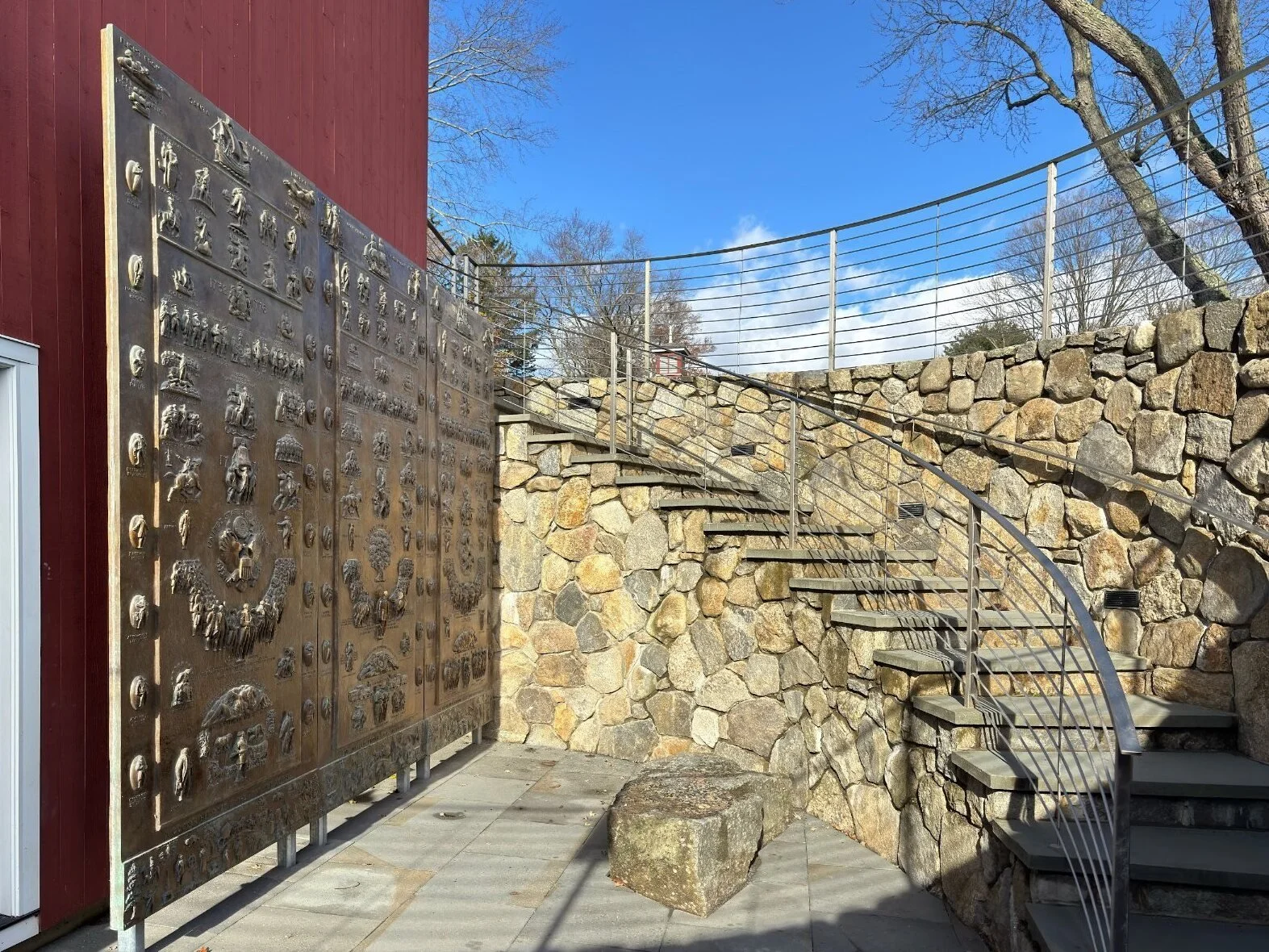 The three bronze Fraser Panels standing side by side in the stone-walled stairwell of the Visitor Center.