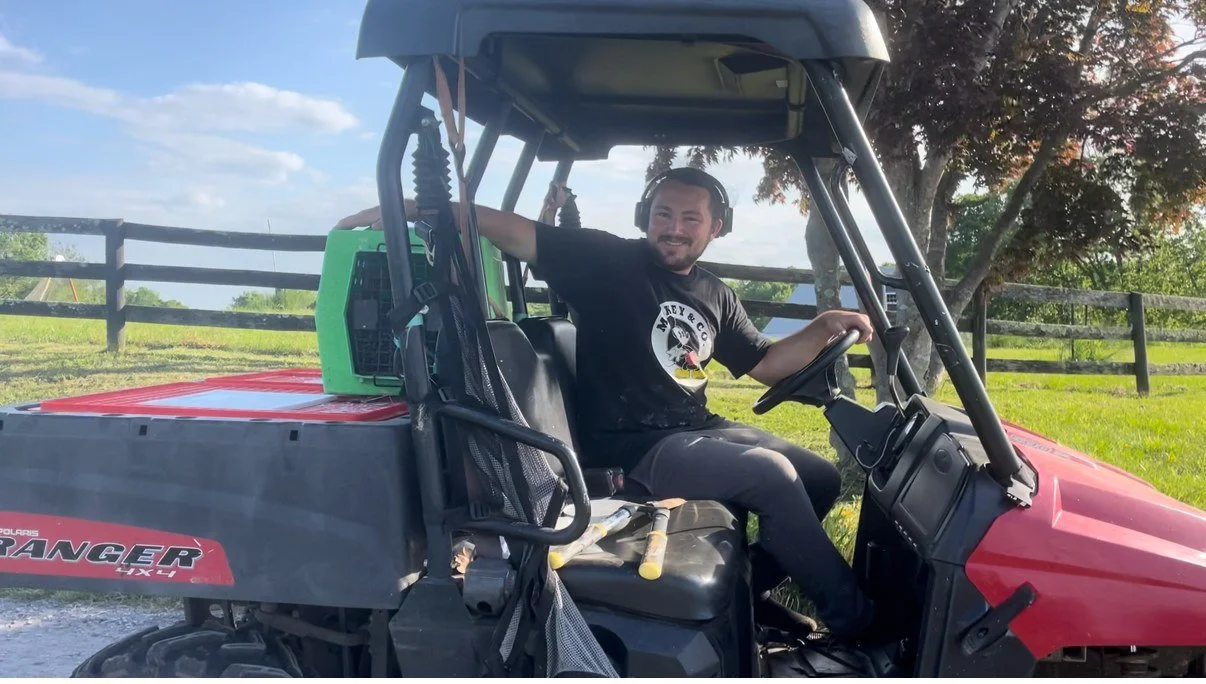 Harrison driving the Chicken School Bus, a red utility vehicle with a chicken crate in back